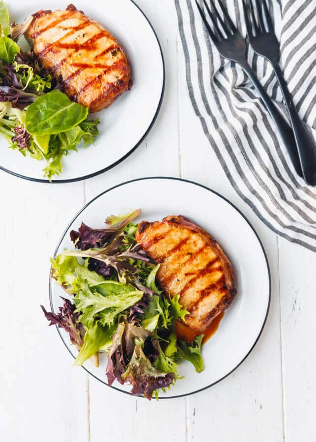Grilled pork chops with mixed greens on plates